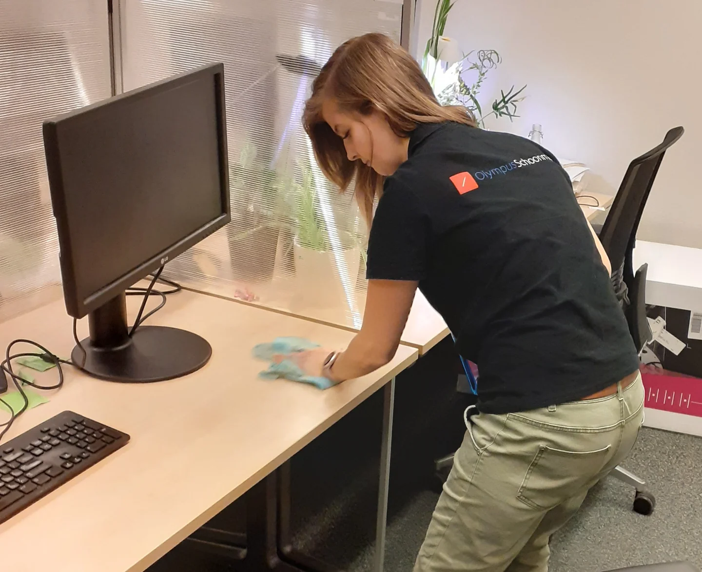 Olympus-medewerker neemt een bureau af; het logo op de werkkleding is zichtbaar