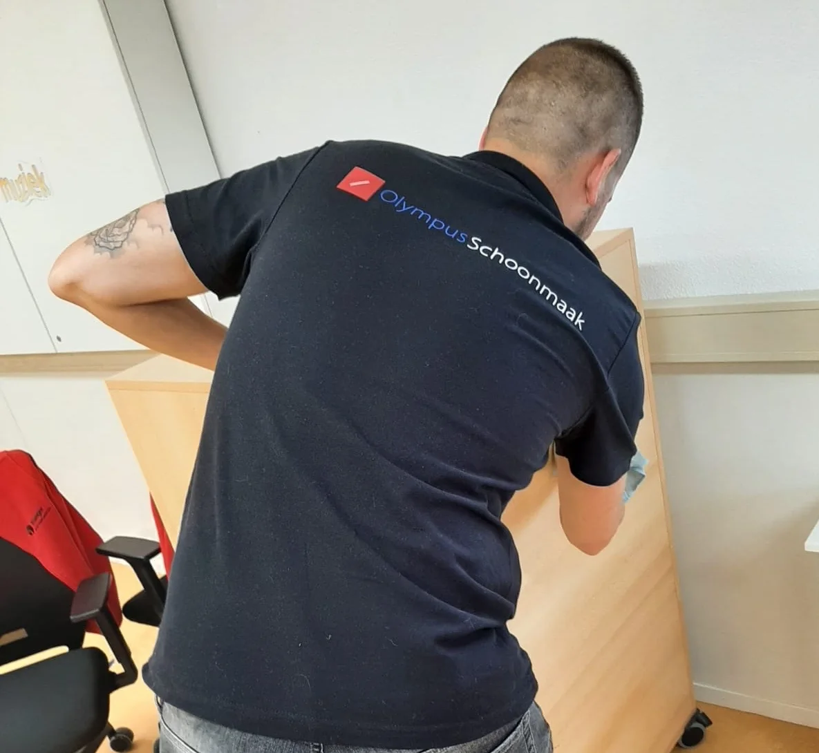 Olympus-medewerker neemt een kast af; het logo op het poloshirt is zichtbaar